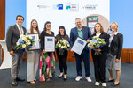 Eine Gruppe von Frauen und Männern hält Blumen und Urkunden in den Händen